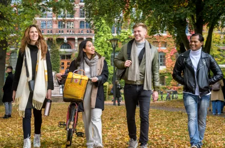 Four students walking in front of the University Library in autumn. Photo by Kennet Ruona.