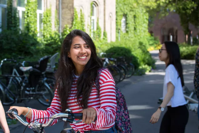 A student holding a bike in front of Gamla Kirurgen. Photo.