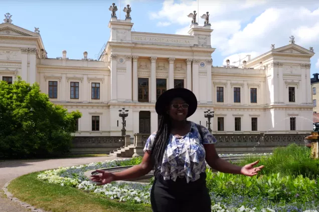 The tour guide in front of the main University Building with their arms outstretched. Photo.