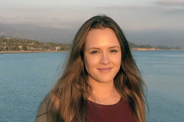 Ina posing in front of a lake and mountains. Photo.