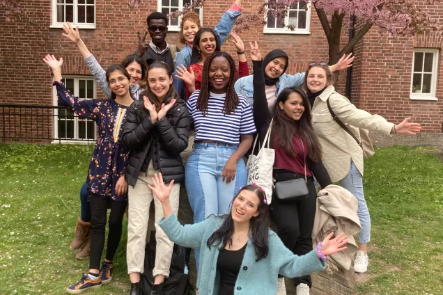 A bunch of students posing in front of a blossoming tree. Photo.