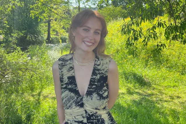 Filippa standing outside, surrounded by green grass and trees. Photo.