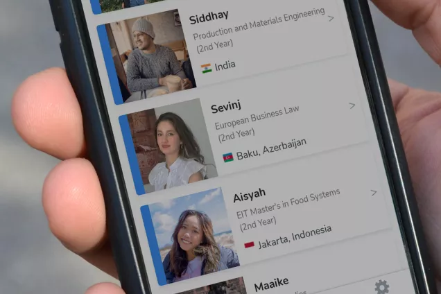 A hand holding a phone with a list of student ambassadors on the display. Photo.