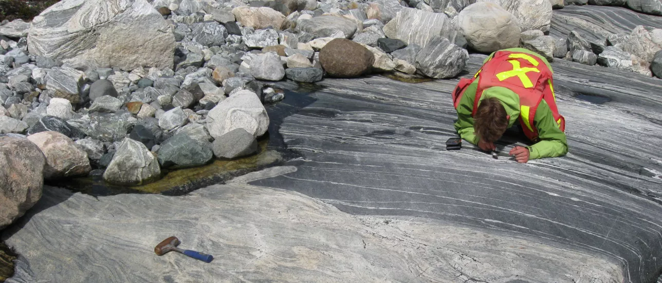 Someone with tools looking very closely at rocks