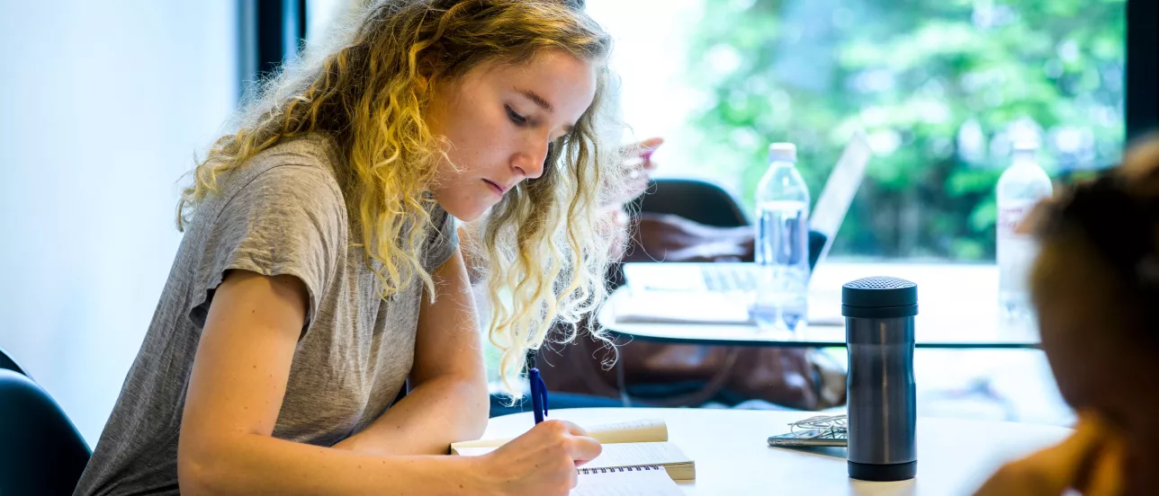 A student writing down something in a notebook during a class