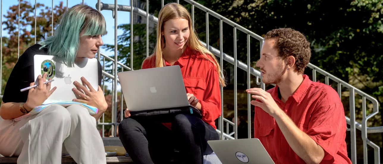 Three students doing group work outside the Social Sciences Faculty