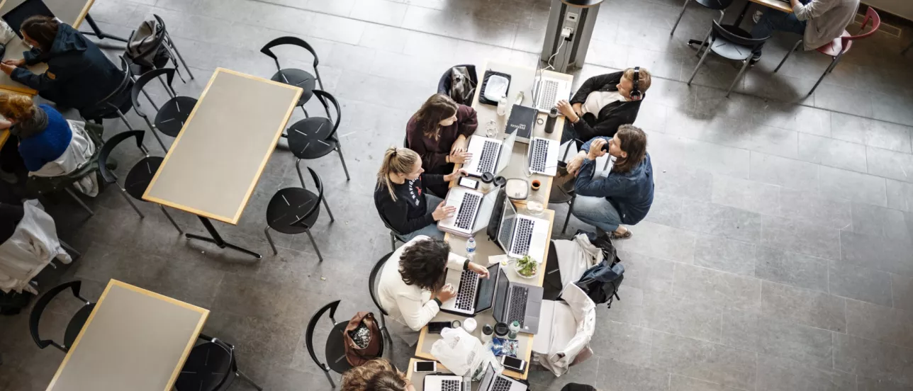 A group of students sitting at a table studying, picture taken from above 