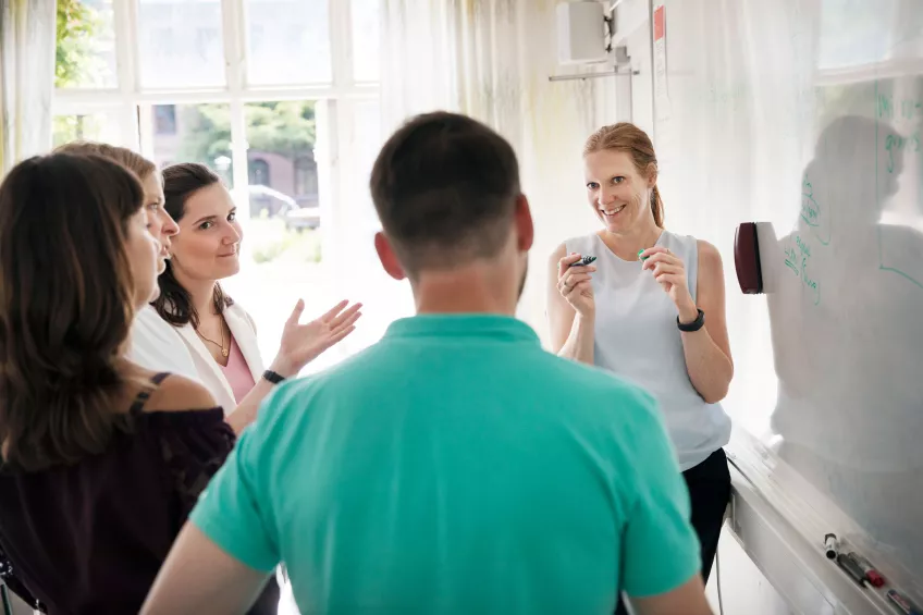 People discussing something in front of a whiteboard