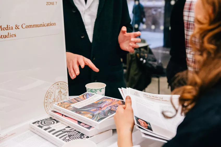 Teaching staff talking to a student about the Media and Communication programme