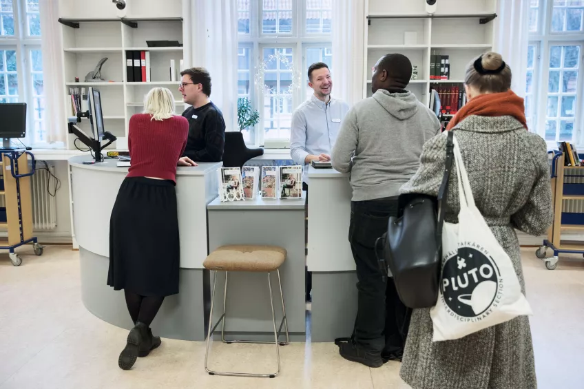 Library staff smiling and talking to students