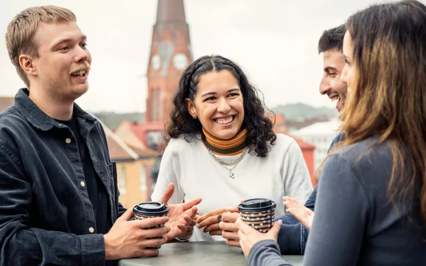 Four students talking while having coffee. Photo.