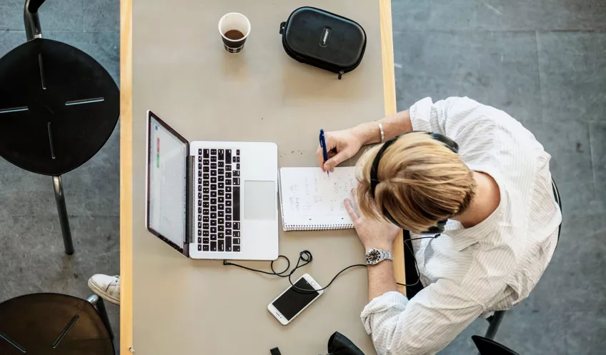 A student studying at a table seen from above. Photo.