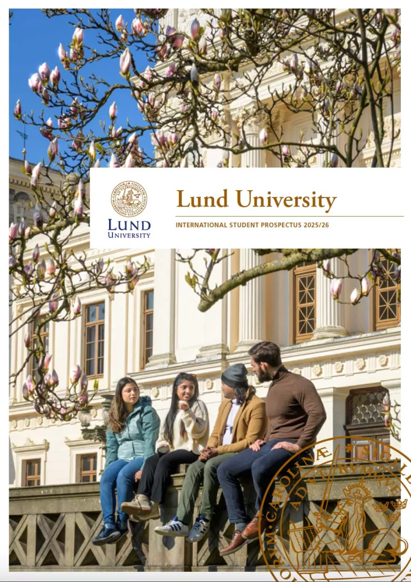 Four students sitting outside of the main university building under the magnolia tree. Photo.