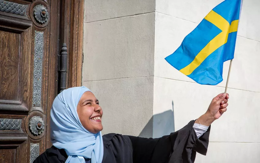 A student wavin the Swedish flag. Photo.