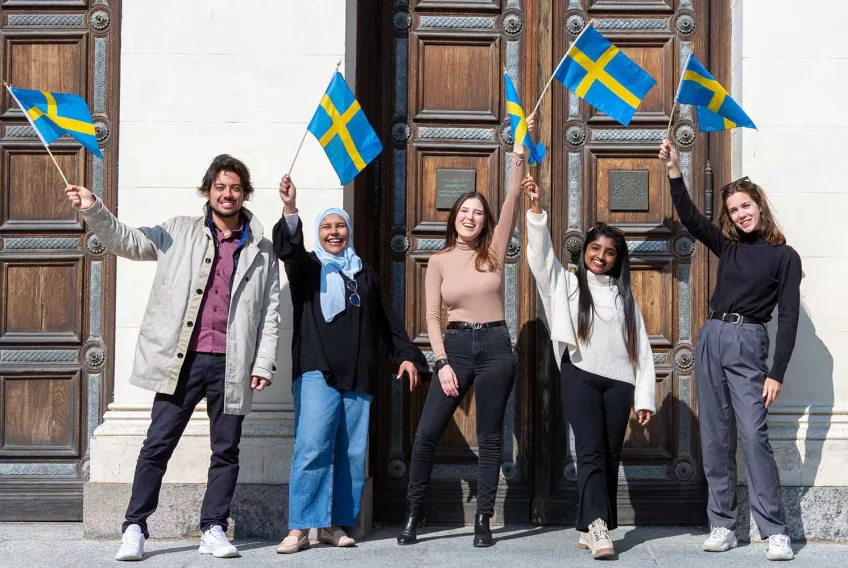 Students waving the Swedish flag outside of the Main University Building. Photo