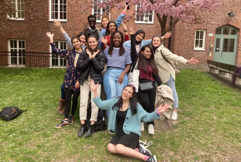 Students making a group formation while smiling at the camera. Photo.