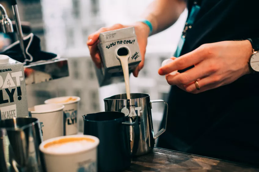 Someone pouring Oatly milk into coffee. Photo: Oatly press images.